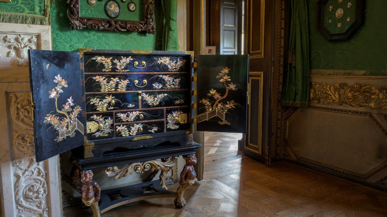 One of the Lacquer Cabinets in the Green Closet at Ham House and Garden, London with a wooden floor in the foreground and a doorway behind